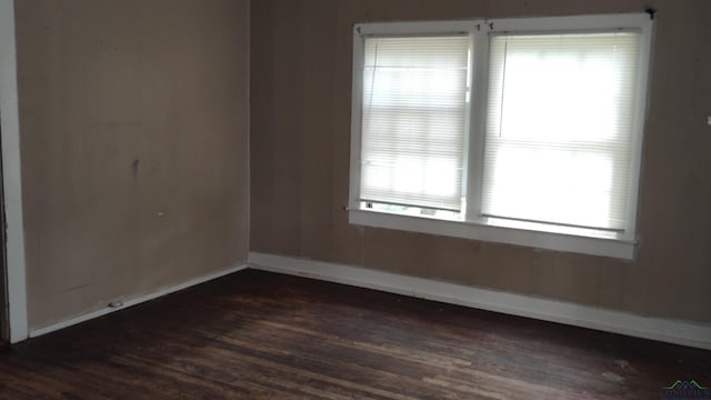 spare room with plenty of natural light and dark hardwood / wood-style flooring