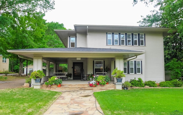 rear view of property featuring covered porch and a yard