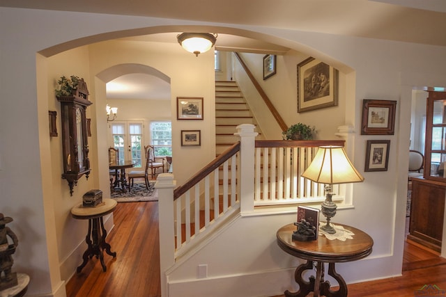 staircase with arched walkways and wood finished floors