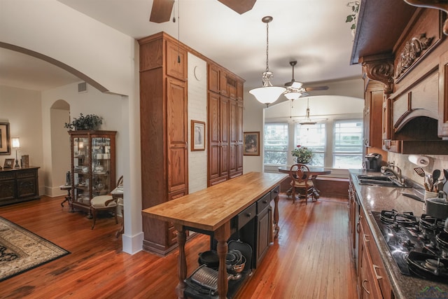 kitchen with a sink, wooden counters, ceiling fan, arched walkways, and black gas stovetop