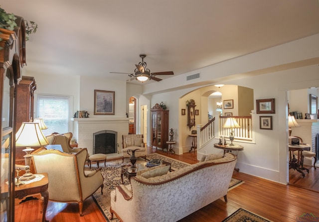 living room with arched walkways, baseboards, a fireplace, and wood finished floors