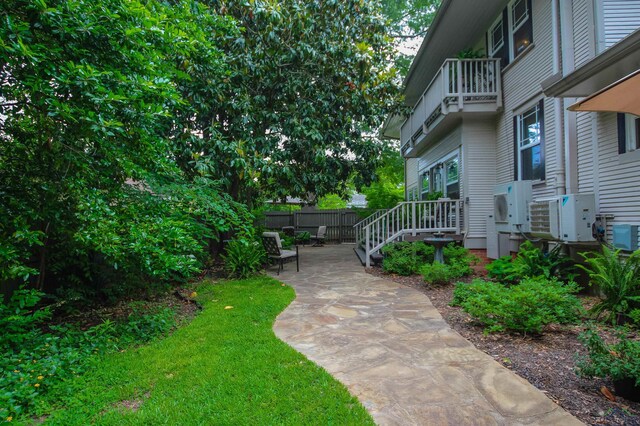view of yard with fence, ac unit, a balcony, and a patio area