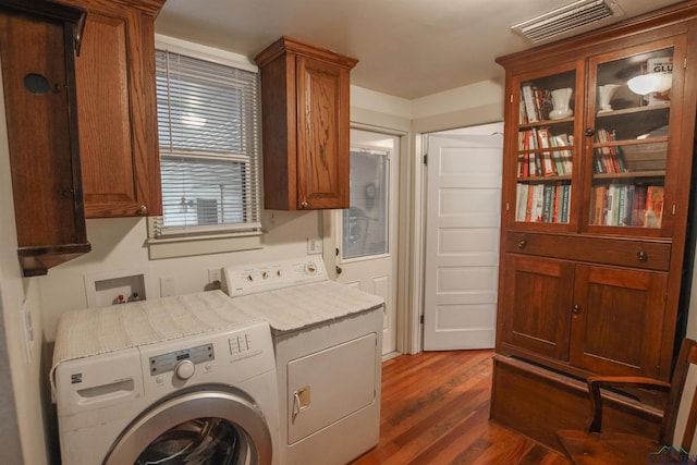 washroom with wood finished floors, independent washer and dryer, cabinet space, and visible vents