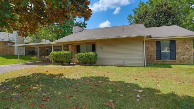 view of front facade with a front yard, a carport, and cooling unit