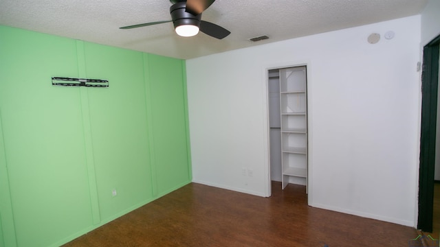 unfurnished bedroom featuring ceiling fan, a closet, a textured ceiling, and dark wood-type flooring