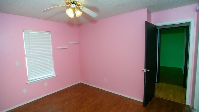 empty room with a textured ceiling, ceiling fan, and dark wood-type flooring