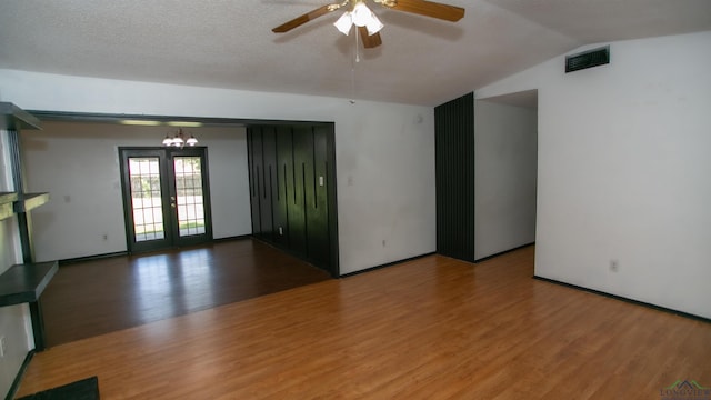 unfurnished room featuring hardwood / wood-style floors, french doors, ceiling fan with notable chandelier, vaulted ceiling, and a textured ceiling