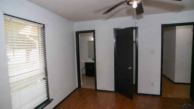 bedroom featuring ceiling fan, ensuite bathroom, dark wood-type flooring, and a textured ceiling