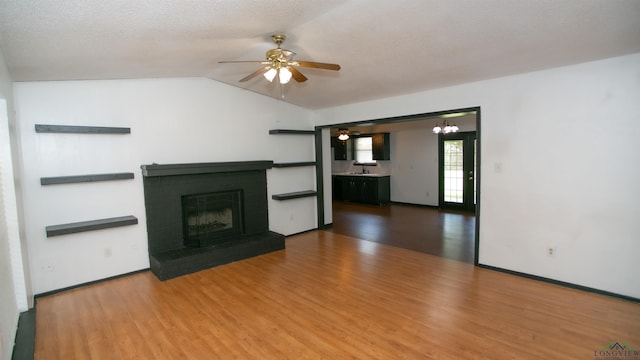 unfurnished living room featuring hardwood / wood-style floors, a textured ceiling, and a brick fireplace