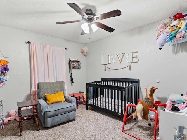 carpeted bedroom with ceiling fan and a crib