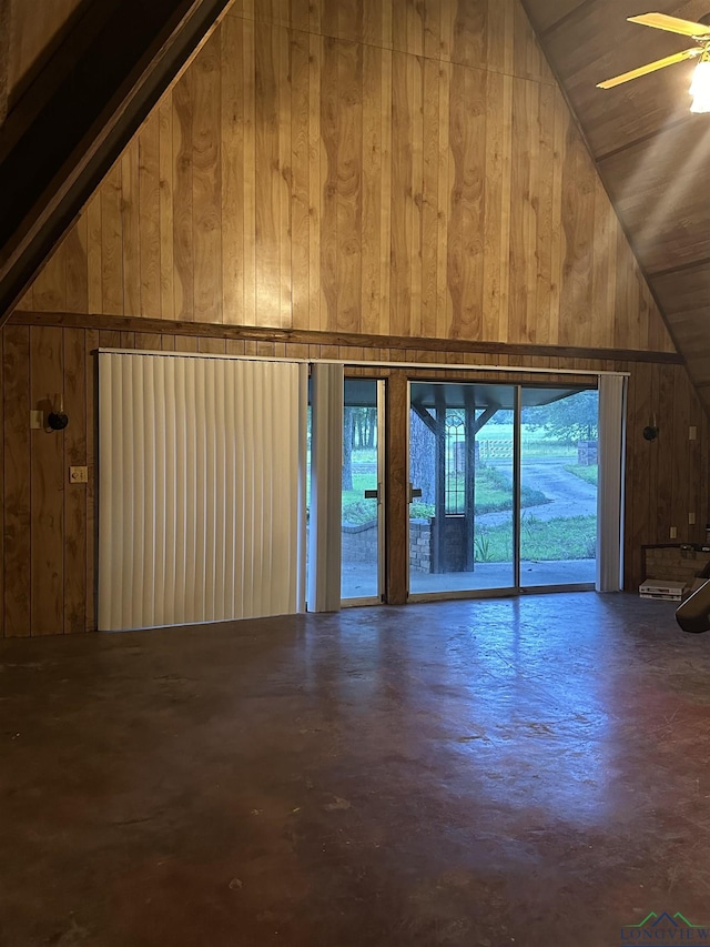 unfurnished living room featuring high vaulted ceiling, concrete floors, and wooden walls