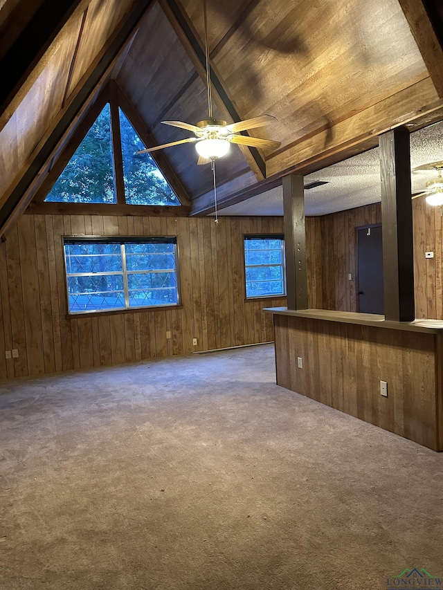 interior space featuring ceiling fan, wooden walls, and vaulted ceiling with beams