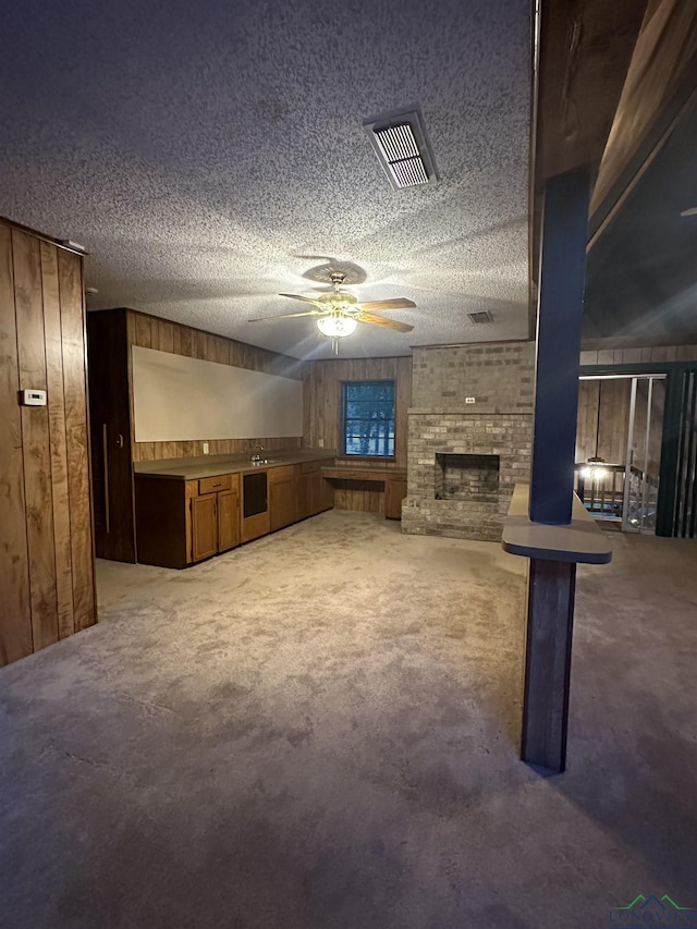 unfurnished living room with sink, a fireplace, a textured ceiling, and wood walls