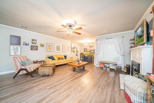 living room with crown molding, ceiling fan, and light wood-type flooring