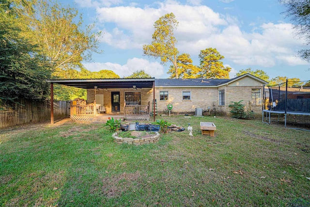 rear view of property featuring a wooden deck, a yard, central AC unit, and a trampoline