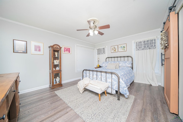 bedroom with hardwood / wood-style floors, crown molding, a barn door, and ceiling fan