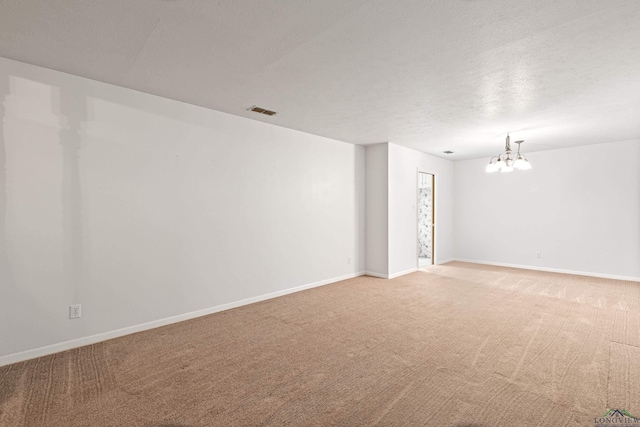 empty room featuring carpet, a chandelier, and baseboards