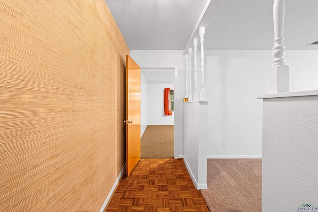 hall featuring carpet flooring, baseboards, and wooden walls