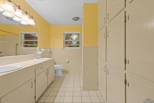 bathroom featuring tile walls, tile patterned floors, toilet, wainscoting, and a shower