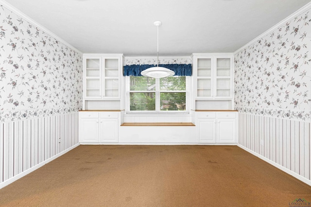 spare room featuring wallpapered walls, dark carpet, ornamental molding, and wainscoting