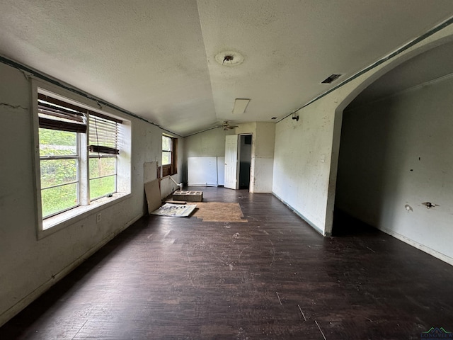 empty room with a textured ceiling, ceiling fan, and vaulted ceiling