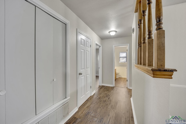 hallway featuring wood-type flooring and a textured ceiling