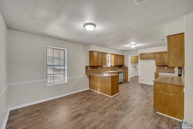 kitchen featuring sink, tasteful backsplash, stainless steel dishwasher, dark hardwood / wood-style flooring, and kitchen peninsula