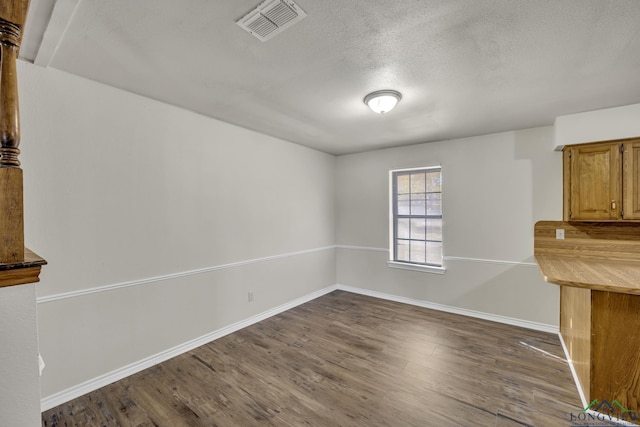 unfurnished dining area with dark hardwood / wood-style floors and a textured ceiling