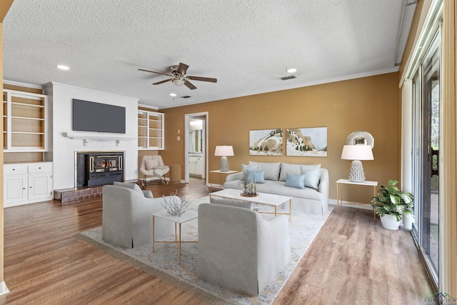 living room with hardwood / wood-style floors, a textured ceiling, ceiling fan, and ornamental molding