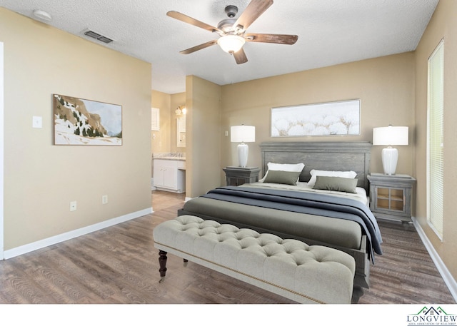 bedroom with hardwood / wood-style floors, a textured ceiling, ensuite bathroom, and ceiling fan