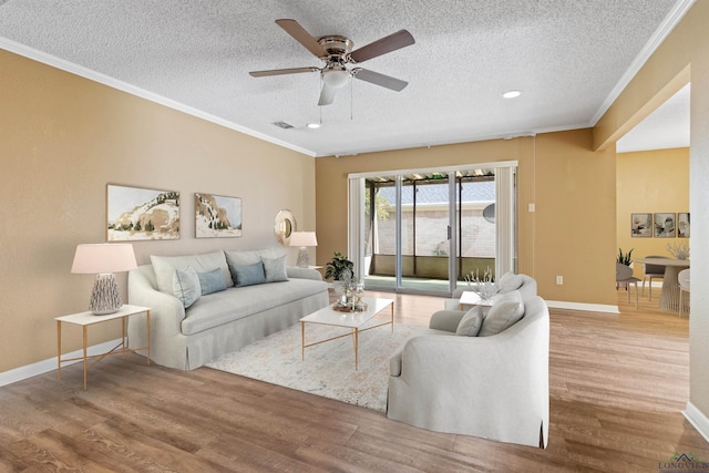 living room with wood-type flooring, a textured ceiling, ceiling fan, and ornamental molding