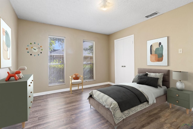 bedroom with a closet, dark hardwood / wood-style floors, and a textured ceiling