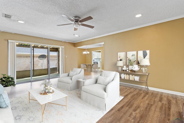 living room with ceiling fan with notable chandelier, crown molding, a textured ceiling, and light hardwood / wood-style flooring