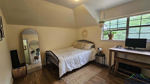 bedroom featuring a textured ceiling, wood finished floors, arched walkways, baseboards, and vaulted ceiling