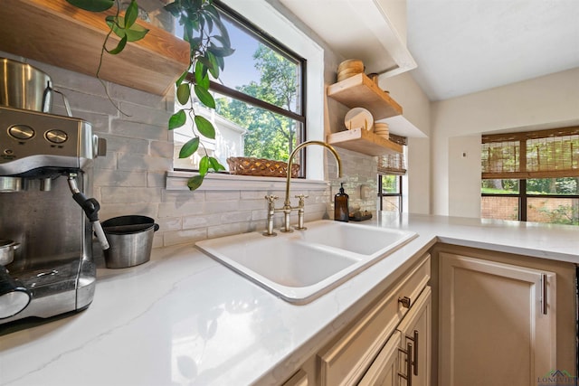 kitchen featuring open shelves, light stone countertops, and a sink