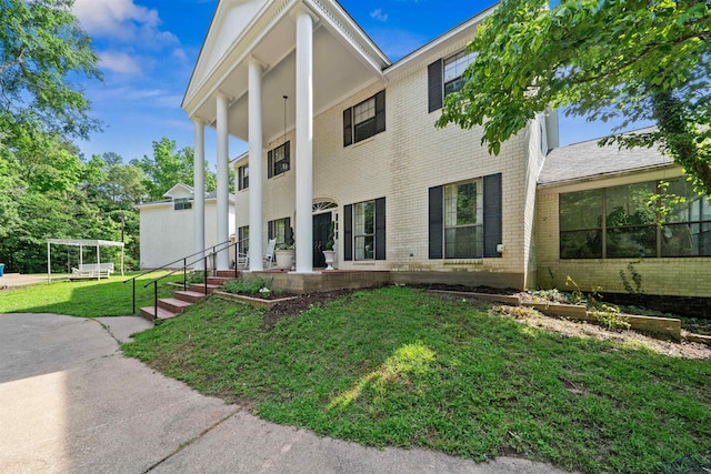 greek revival inspired property with brick siding and a front lawn