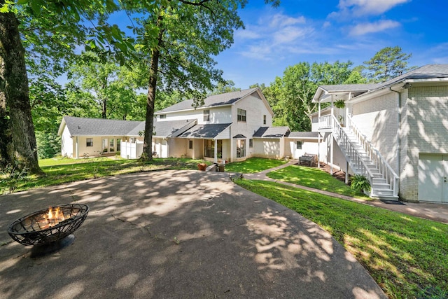 view of front of home with a front yard, stairway, and an outdoor fire pit