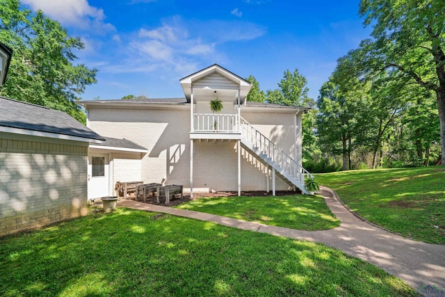 rear view of property with a yard, brick siding, and stairway