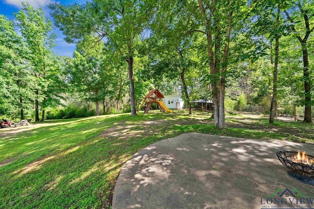 view of yard with a patio, a playground, and a fire pit