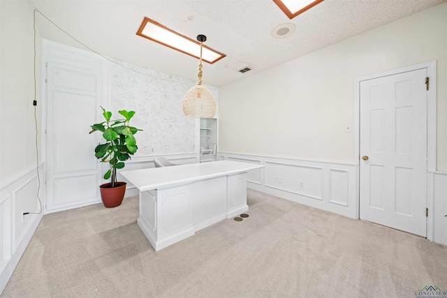 interior space featuring visible vents, light carpet, a textured ceiling, and a decorative wall