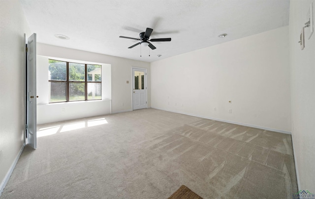 empty room featuring baseboards, light carpet, and a ceiling fan