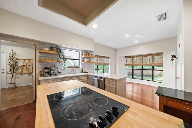 kitchen featuring a sink, dishwasher, dark wood-style floors, black electric cooktop, and open shelves