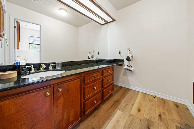 bathroom featuring baseboards, wood finished floors, and vanity