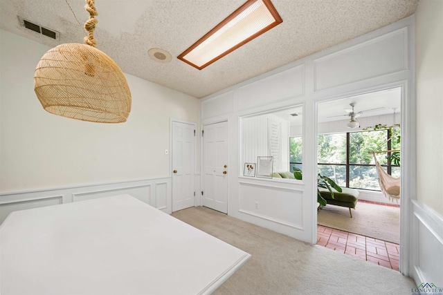 bedroom featuring a wainscoted wall, a decorative wall, visible vents, and a textured ceiling