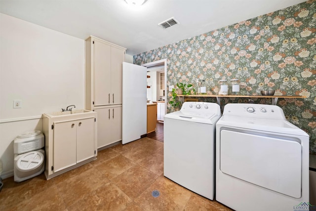 clothes washing area with visible vents, cabinet space, separate washer and dryer, and wallpapered walls
