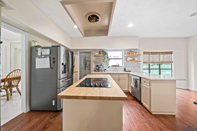 kitchen with wooden counters, a kitchen island, a peninsula, stainless steel appliances, and open shelves