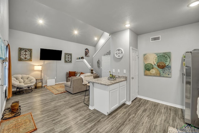 interior space featuring white cabinetry, light stone counters, wood-type flooring, and stainless steel refrigerator