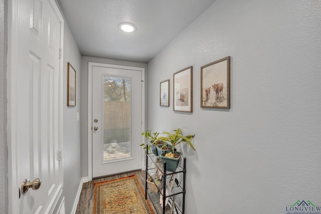 doorway with wood-type flooring and a textured ceiling