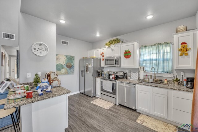 kitchen featuring kitchen peninsula, stainless steel appliances, sink, white cabinets, and a breakfast bar area