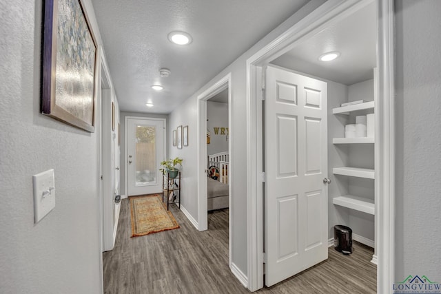 hallway featuring light wood-type flooring and a textured ceiling